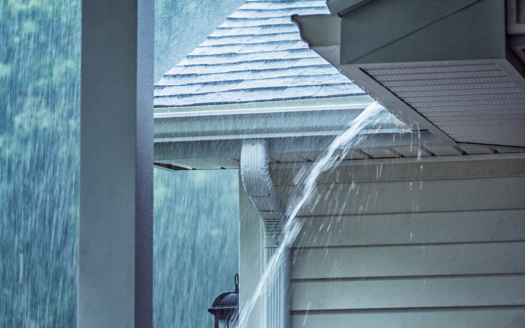 Heavy rain falling on the roof of a modern Phuket villa, emphasizing the lush surroundings and seasonal weather.